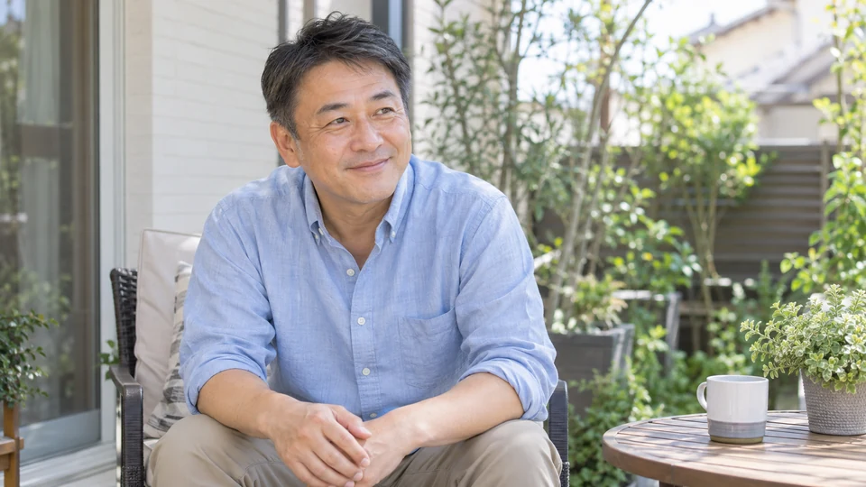 屋外の柔らかな光の中で、男性が自然な表情を見せる。